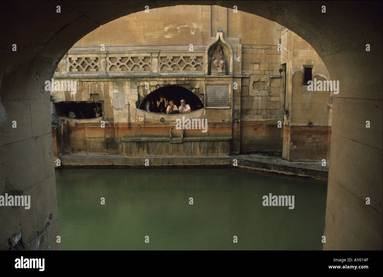 Window From Rome Baths tourist looking through arched window at the roman baths in Bath ...