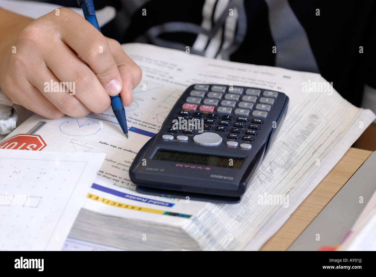 Closeup of college student using calculator and pen for maths lesson
