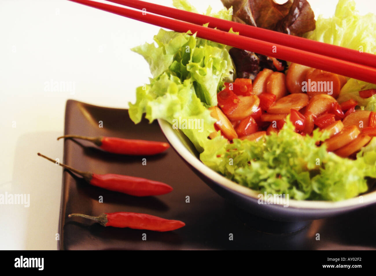 Stirfry in a bowl of greens with chopsticks Stock Photo