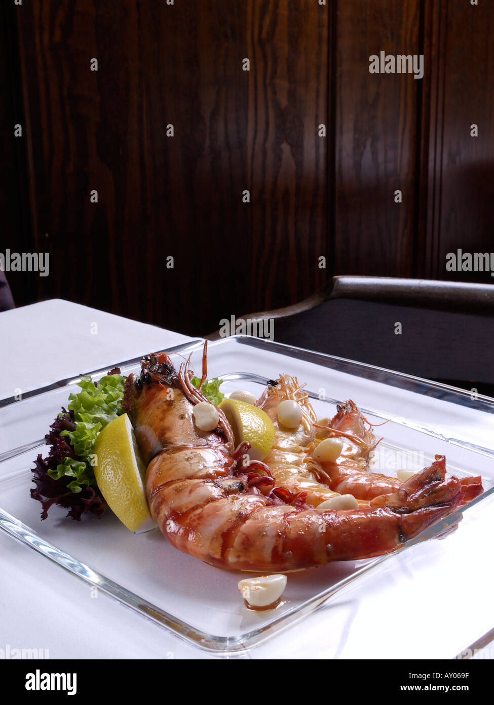 Three gambas of different sizes on a square glass plate in a restaurant Stock Photo