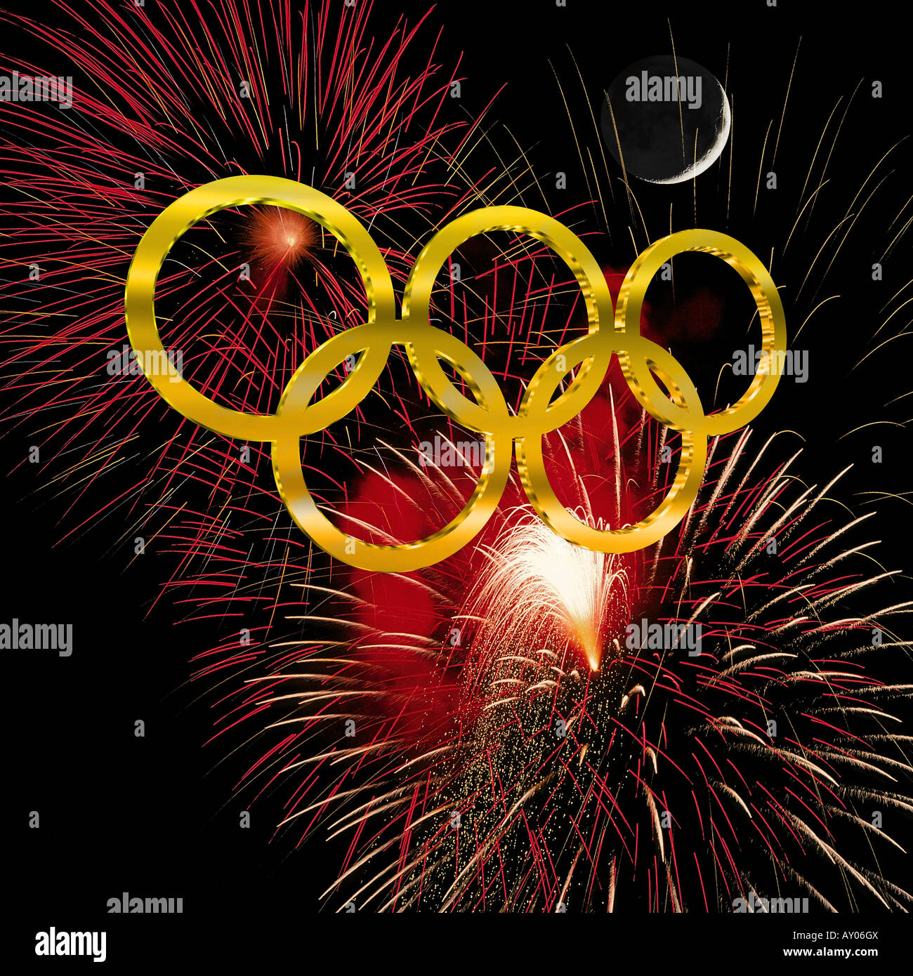Golden olympic rings against a night sky filled with fireworks and a