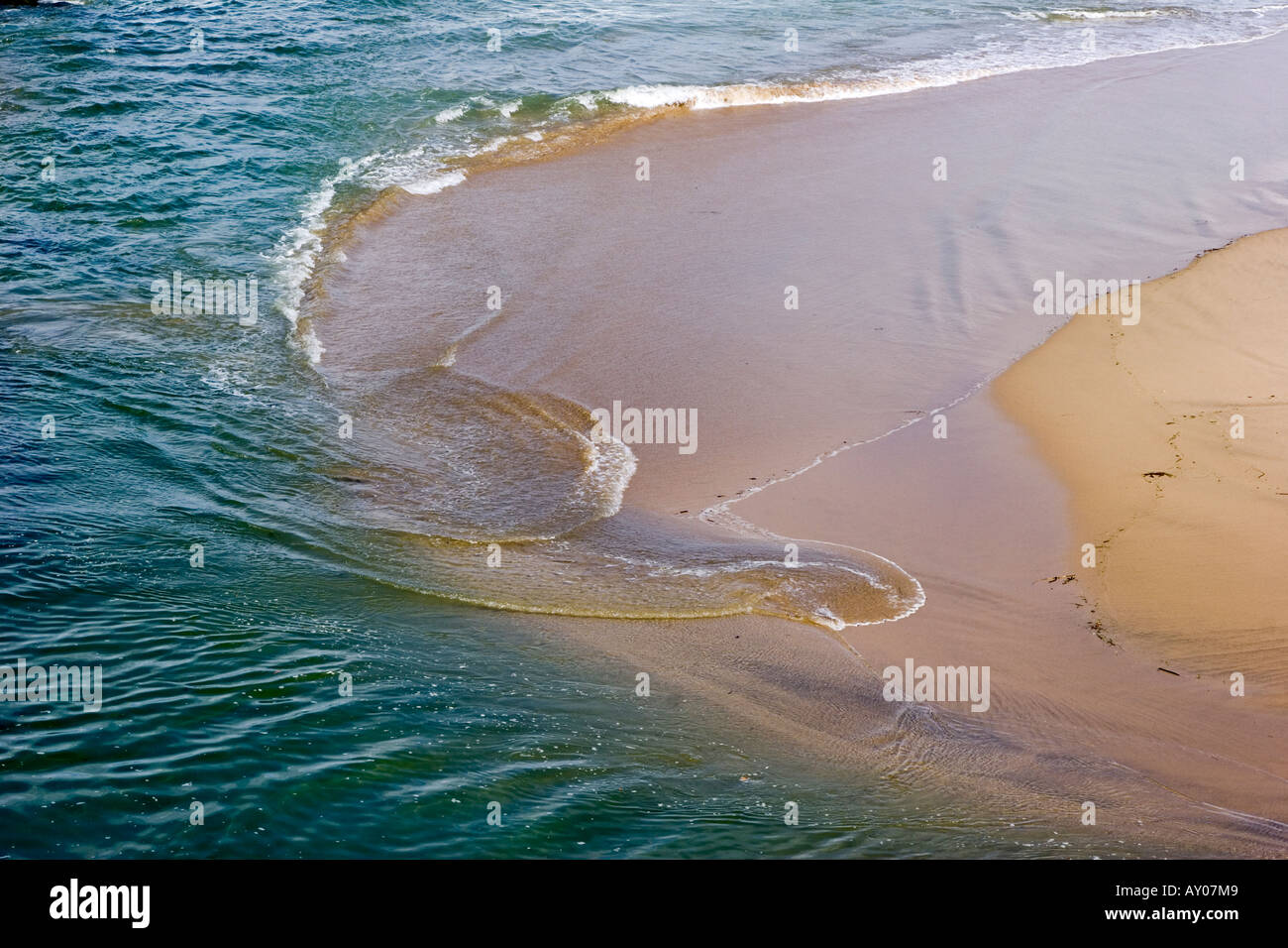 Receding surf forming an abstract pattern in the sand Stock Photo
