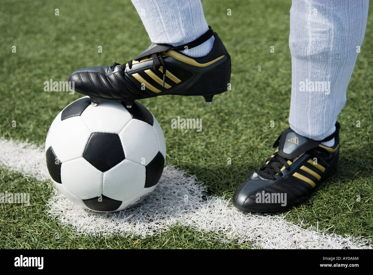 the feet of a football player in white stockings and a vintage black and white football Stock Photo