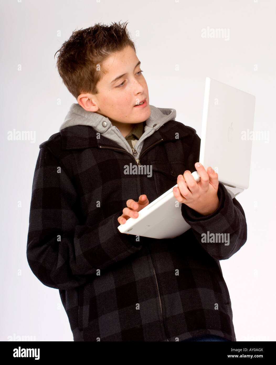 A teenage boy using an Apple MacBook laptop computer in his arms. Picture by Jim Holden Stock Photo