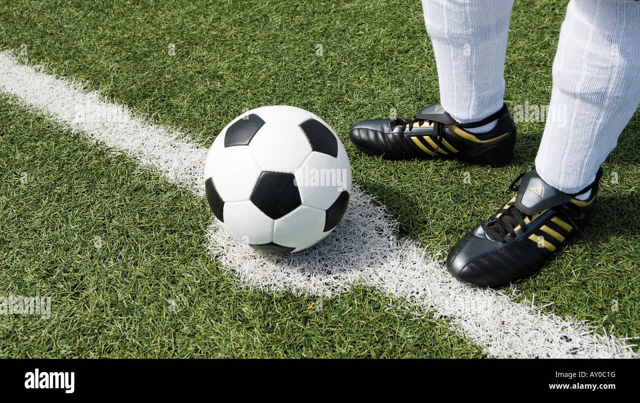 the feet of a football player in red stockings and a vintage black and white football Stock Photo