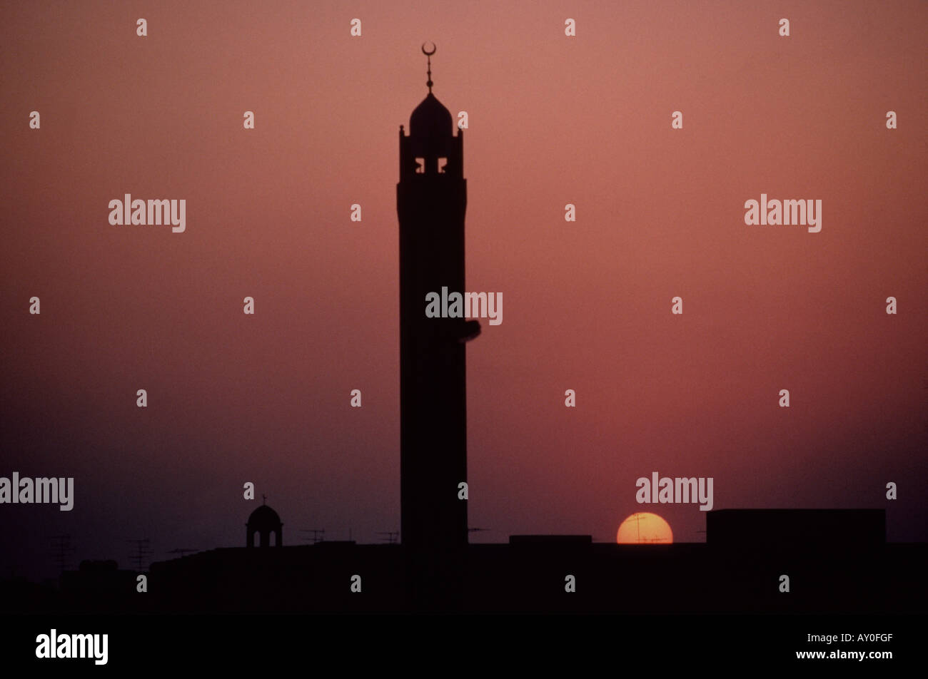 lone minaret shot against a warm red and orange sunset with a yellow sun in al khobar saudi arabia Stock Photo