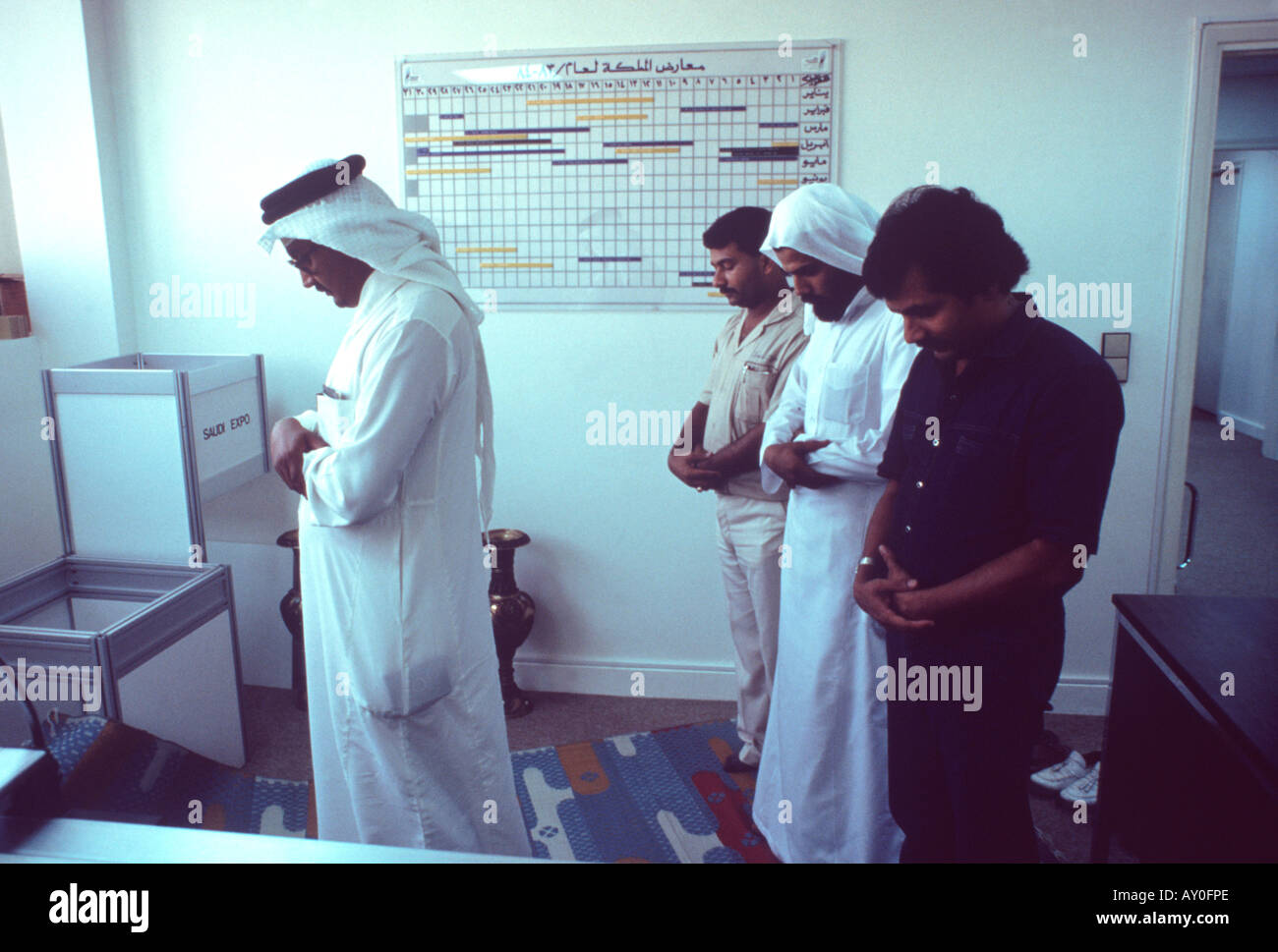 saudi workers taking time out to pray in their office facing east to