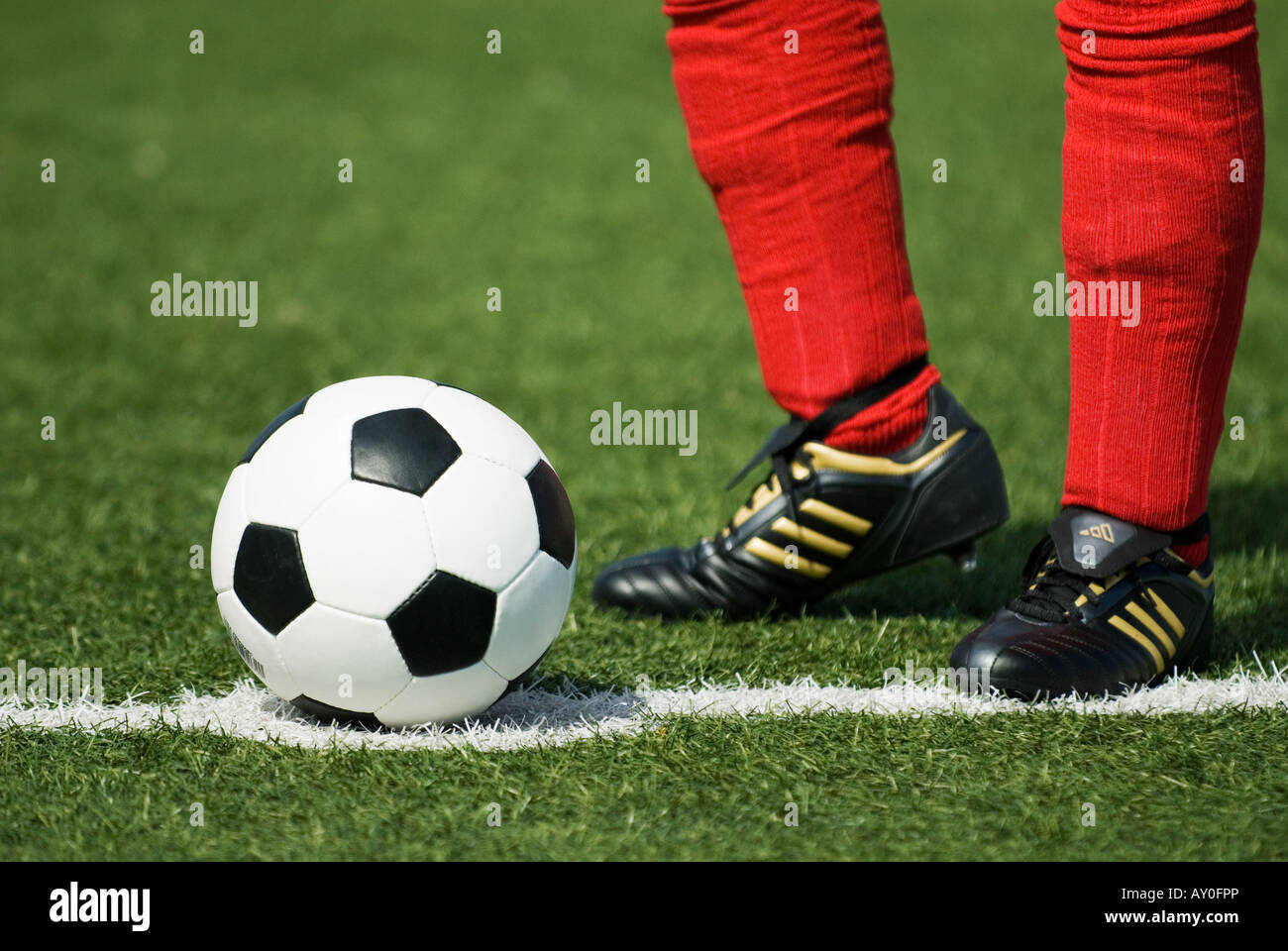 the feet of a football player in red stockings and a vintage black and white football Stock Photo
