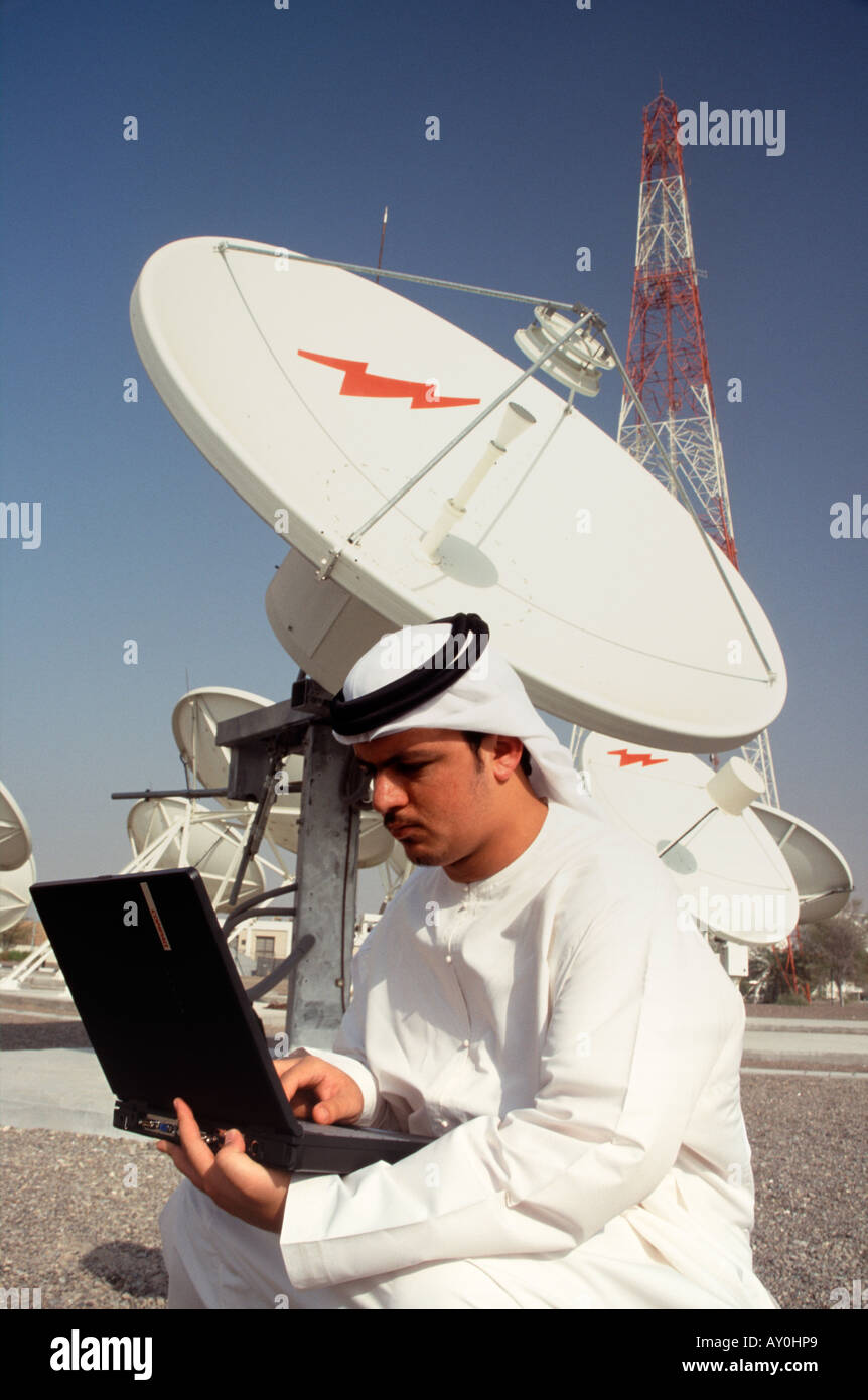 Arab using lap top computer on roof of satellite relay station in the united arab emirates uae Stock Photo