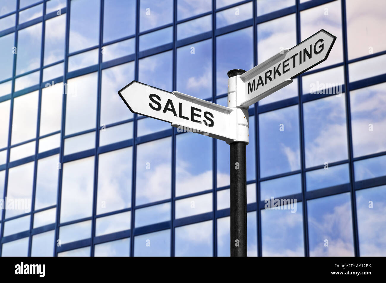 Concept image of Sales Marketing on a signpost against a modern glass office building Stock Photo
