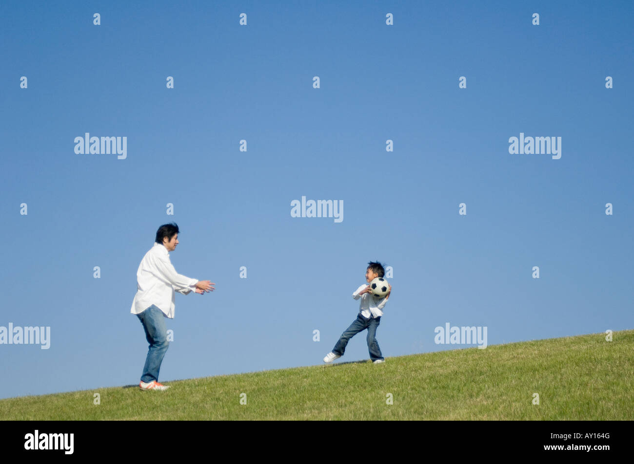 Father and son playing with soccer ball Stock Photo
