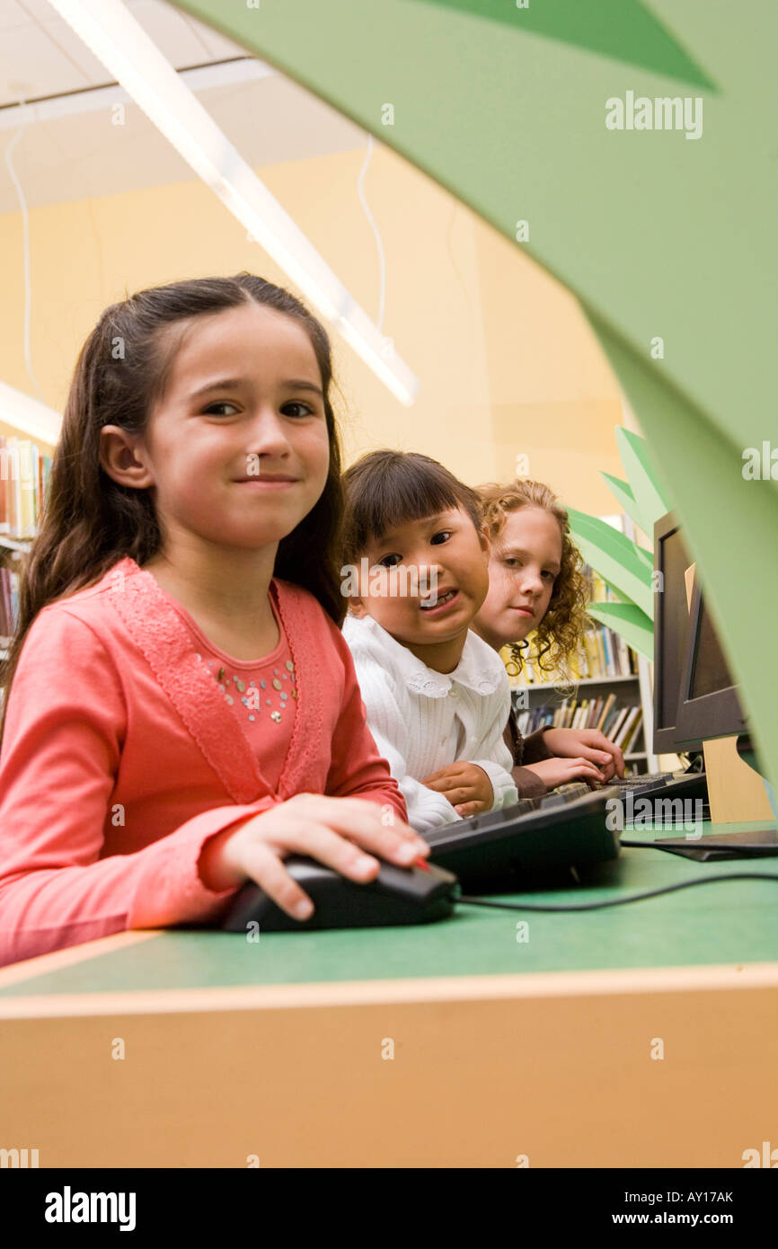Portrait of schoolgirls sitting at computer in the library Stock Photo ...