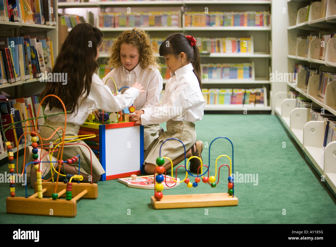 Schoolgirls arranging toys on floor in the library Stock Photo