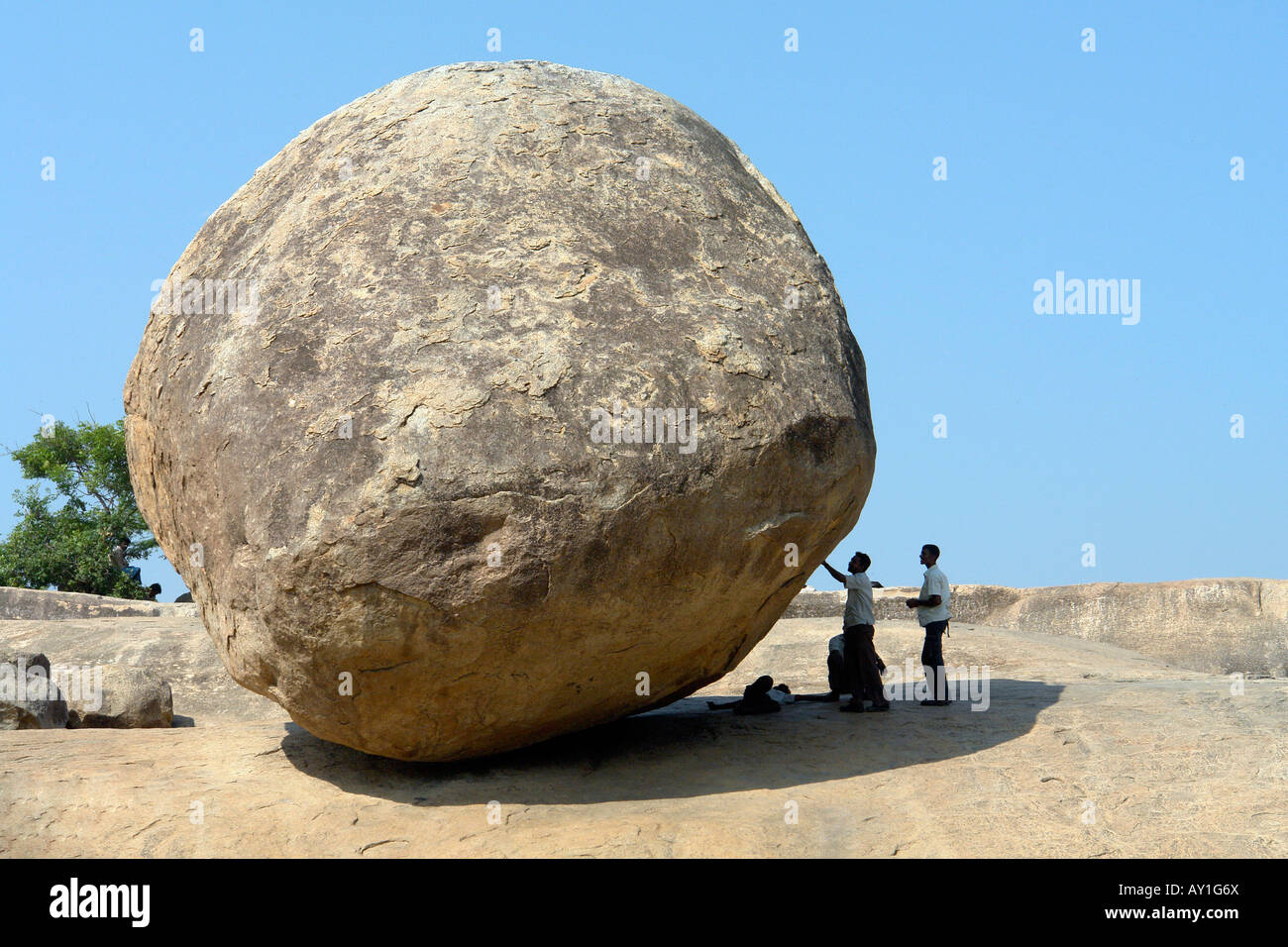 indian visitors investigating krishnas butter ball at mamallapuram Stock Photo