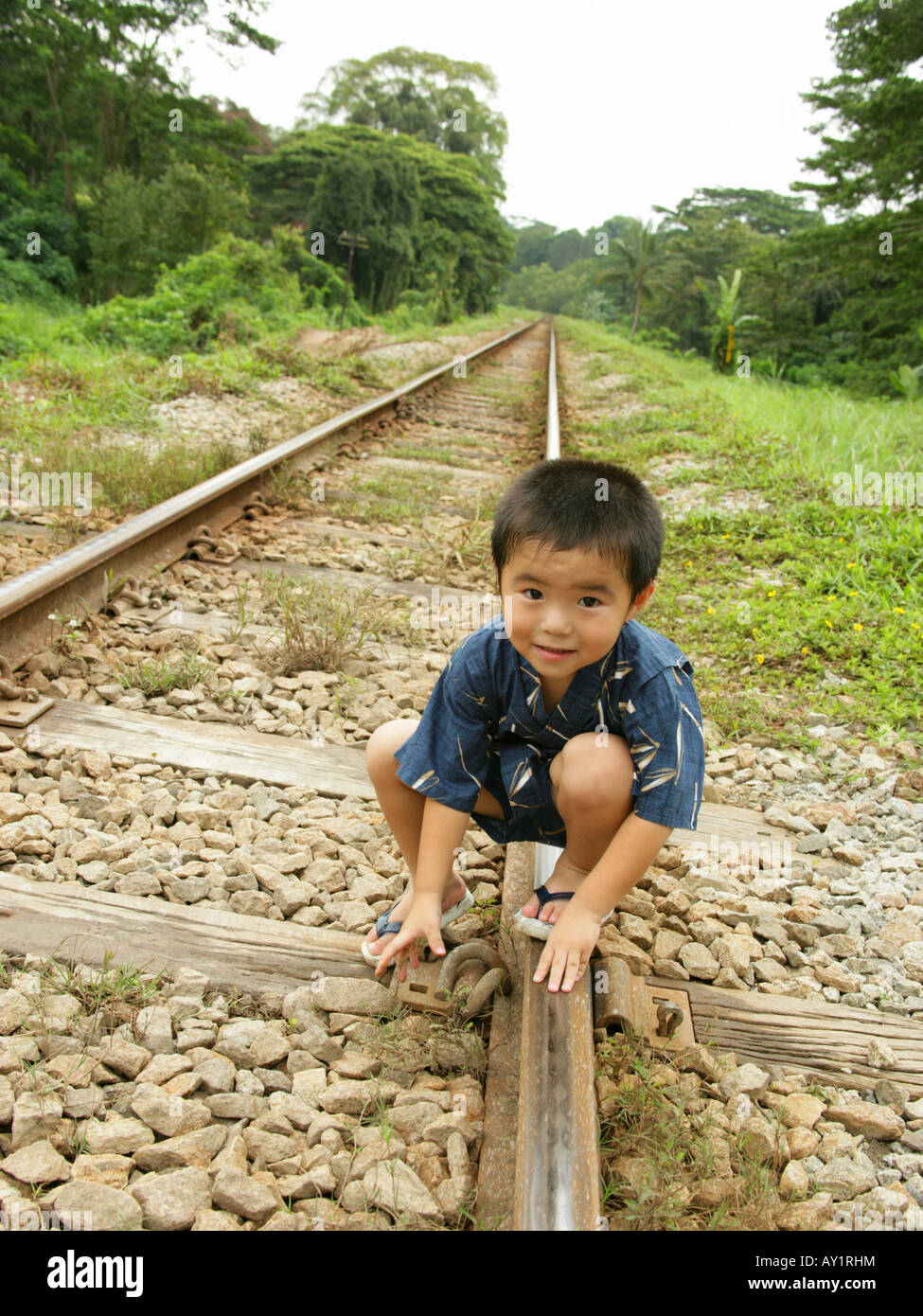 Portrait of a boy squatting on railroad tracks Stock Photo Alamy