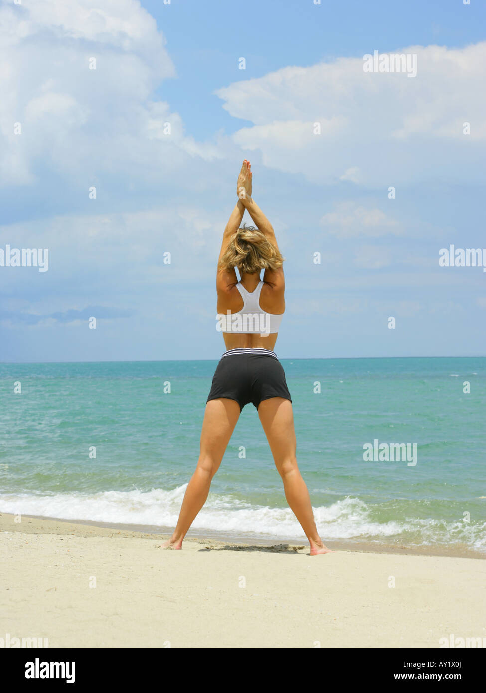 Rear view of a young woman in a yoga pose on the beach Stock Photo - Alamy