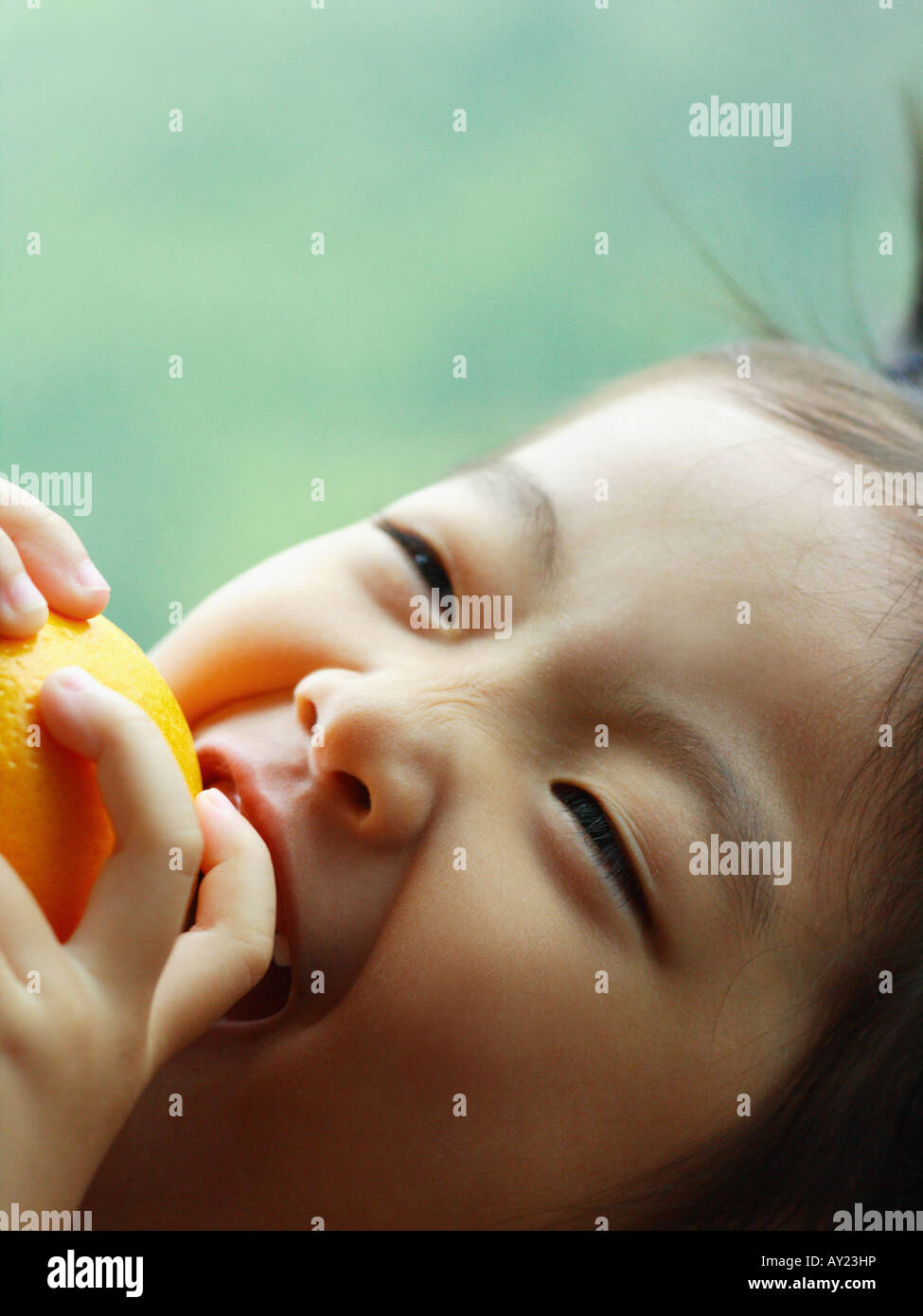 Portrait of a girl biting an orange Stock Photo - Alamy