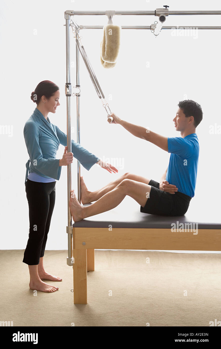 Instructor helping man on exercise equipment Stock Photo