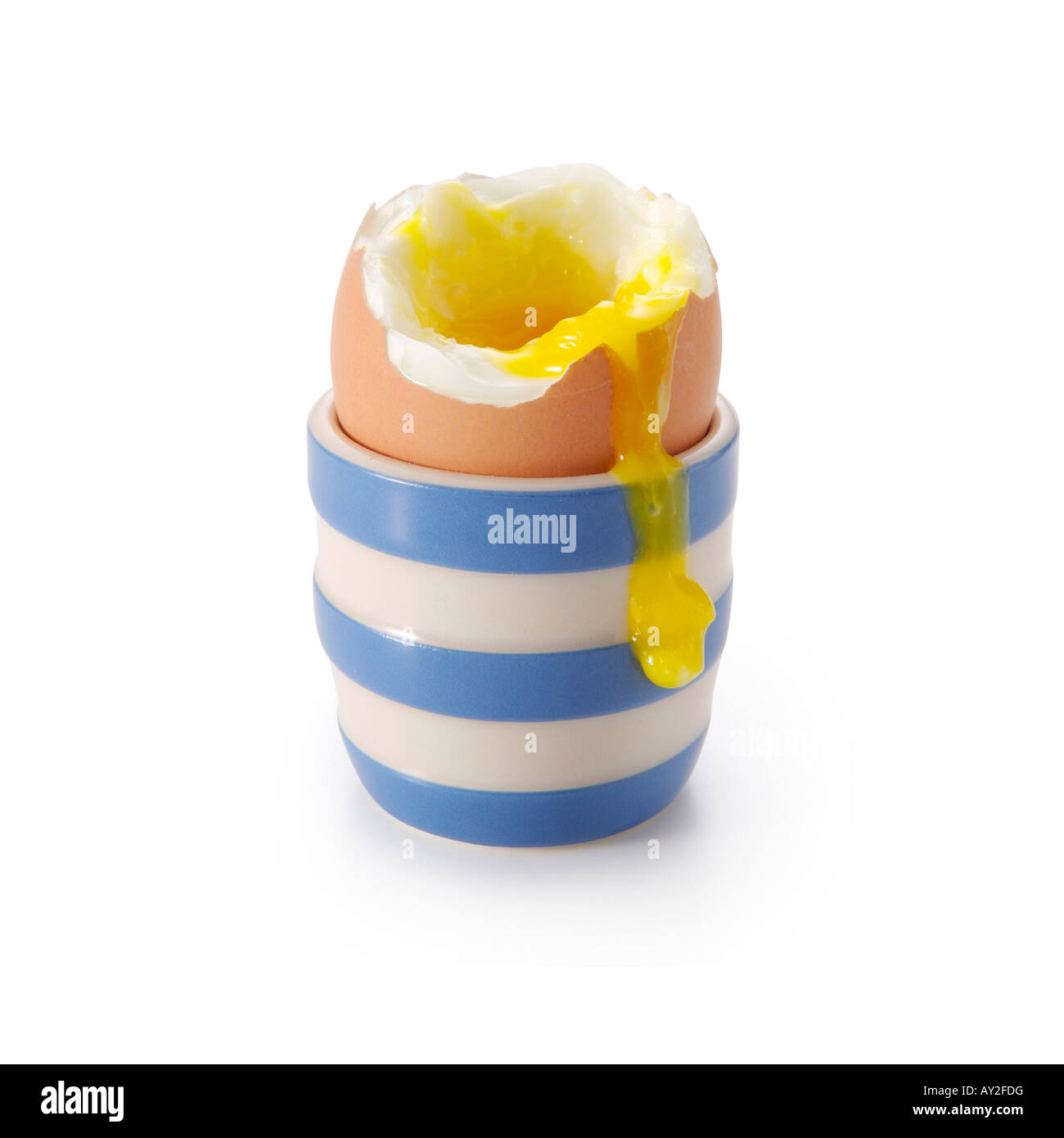 Boiled egg in stripy cup with runny yoke. Stock Photo