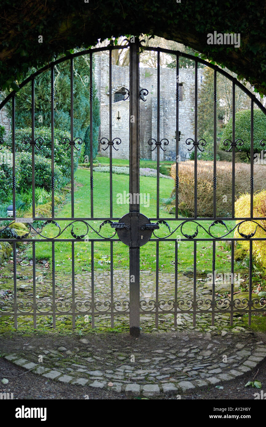 Looking through a pair of closed and locked arched iron gates into a private and secluded garden