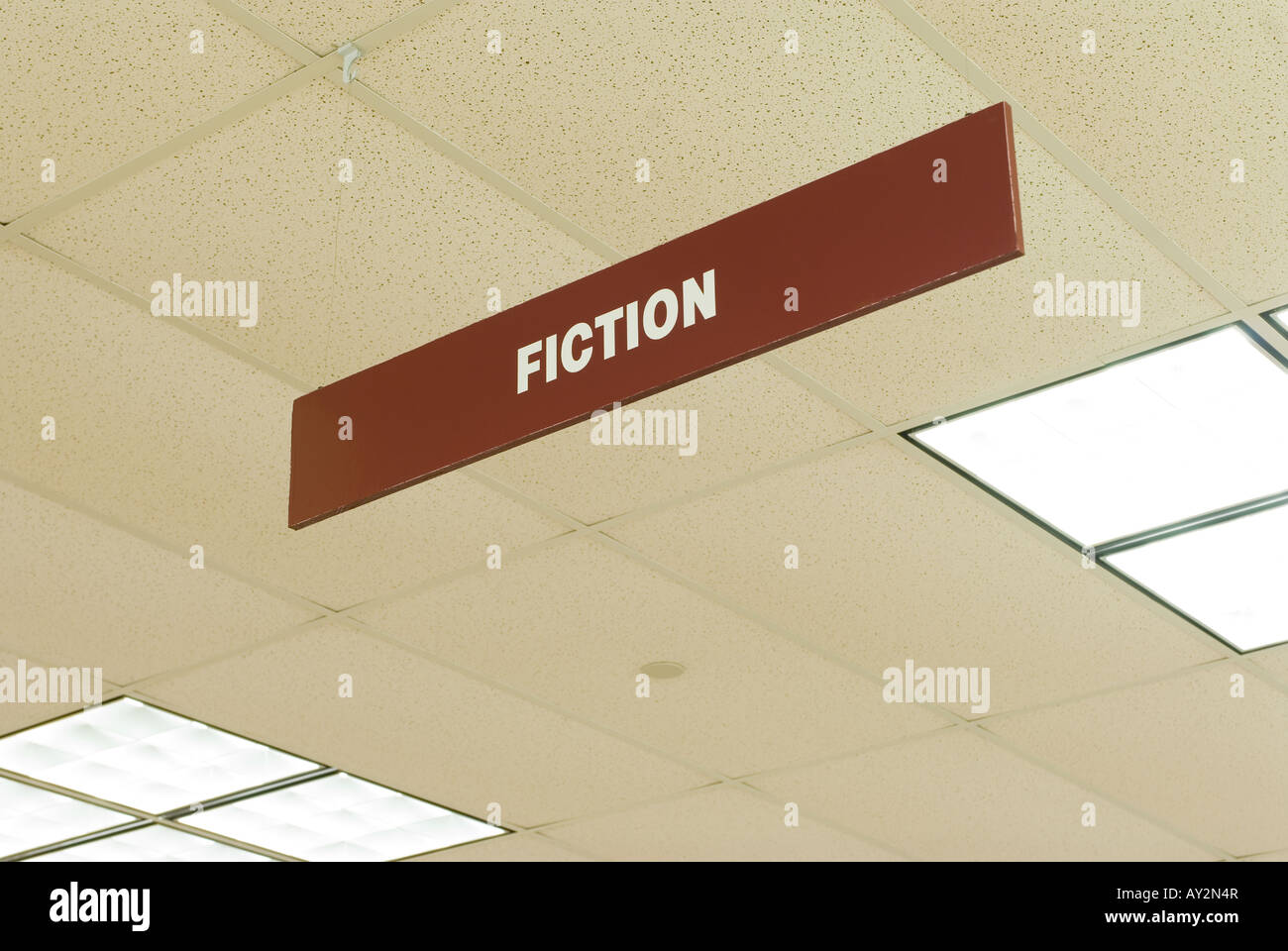 a sign hanging from a library ceiling indicates the fiction section