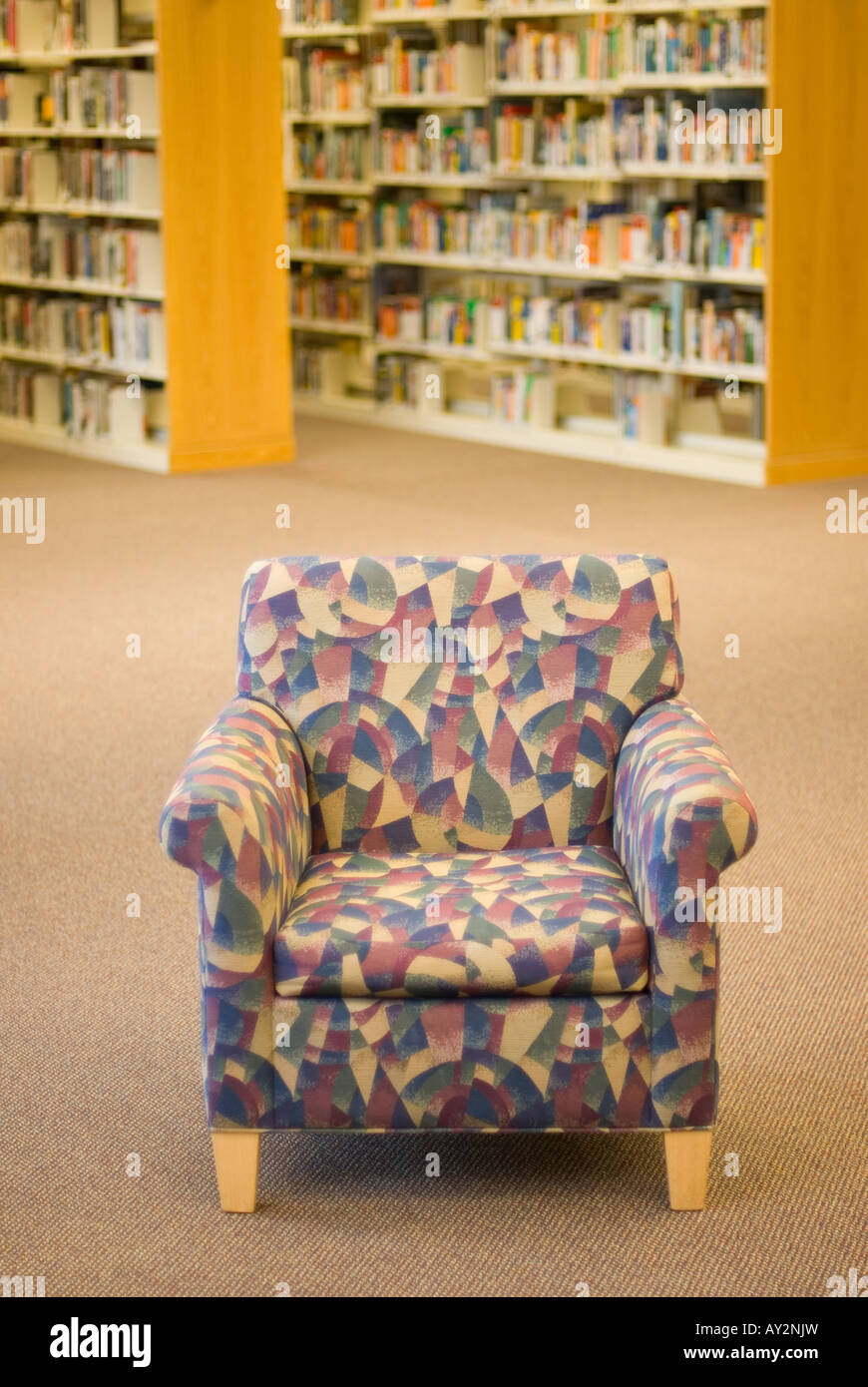 a reading chair in a library with book stacks in the background Stock Photo