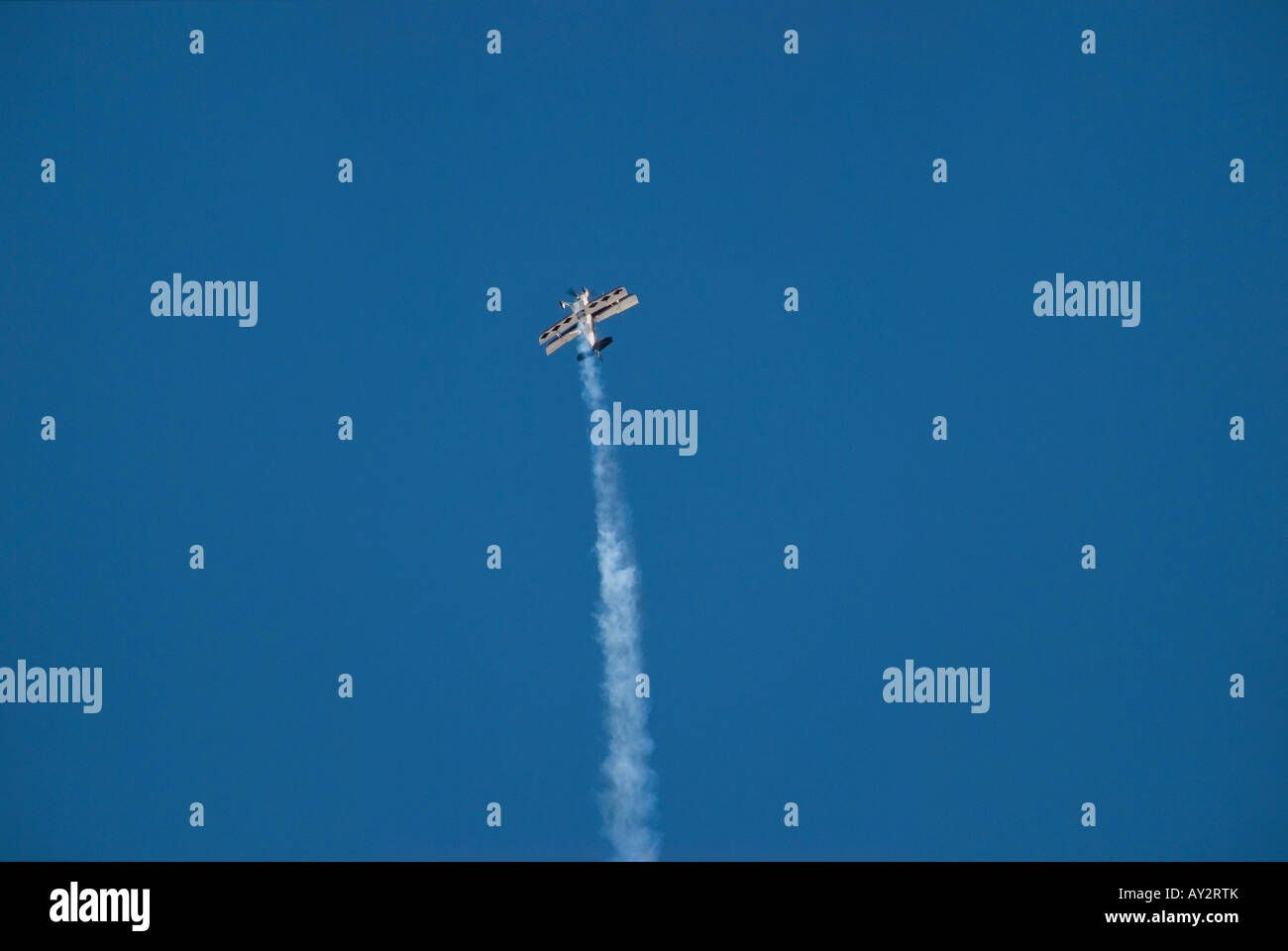Vintage biplane performing stunts at an air show against clear blue sky Stock Photo