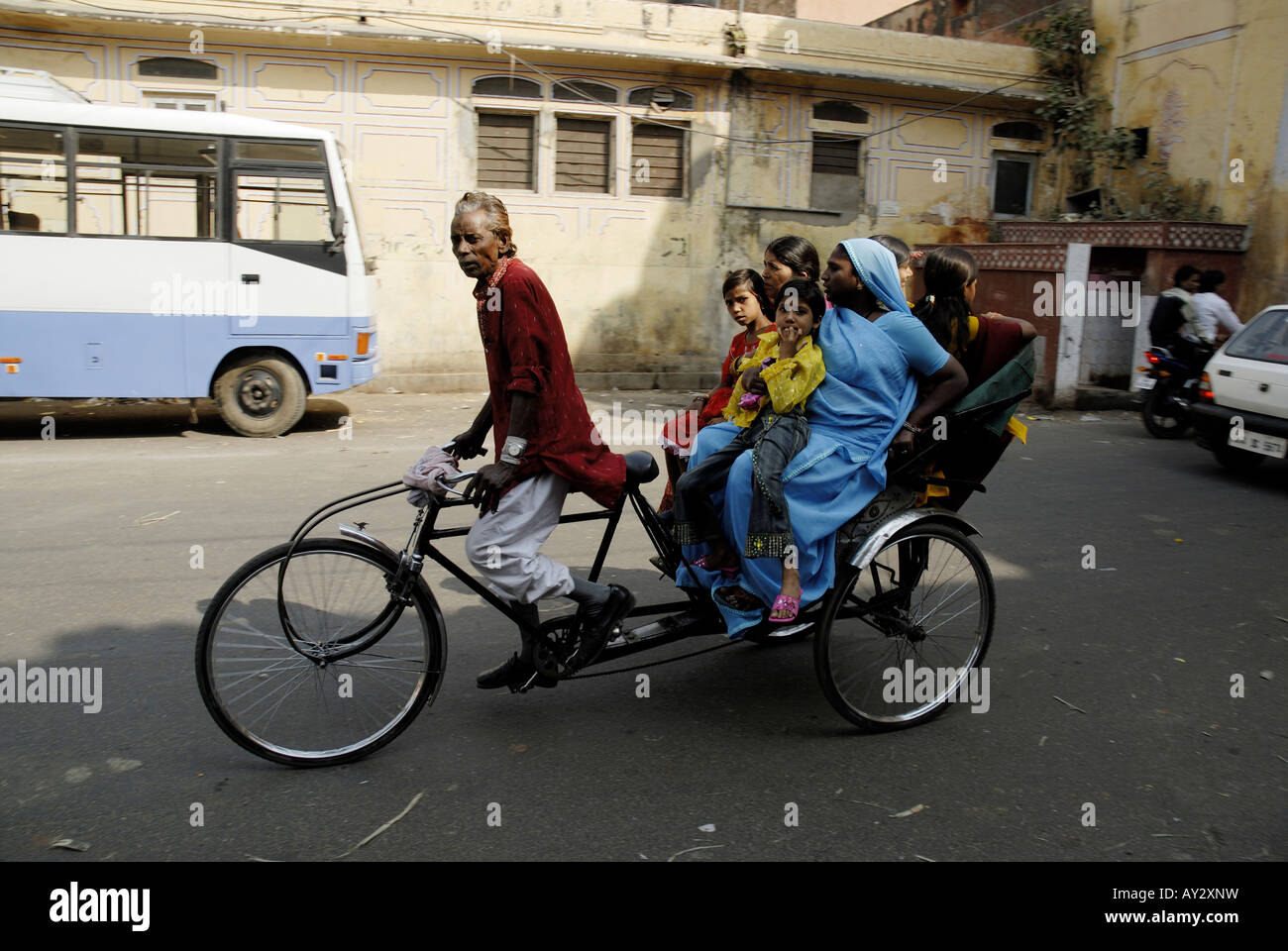 Rickshaw driver struggling to pedal with a loaded carriage. Jaipur Rajasthan India Stock Photo