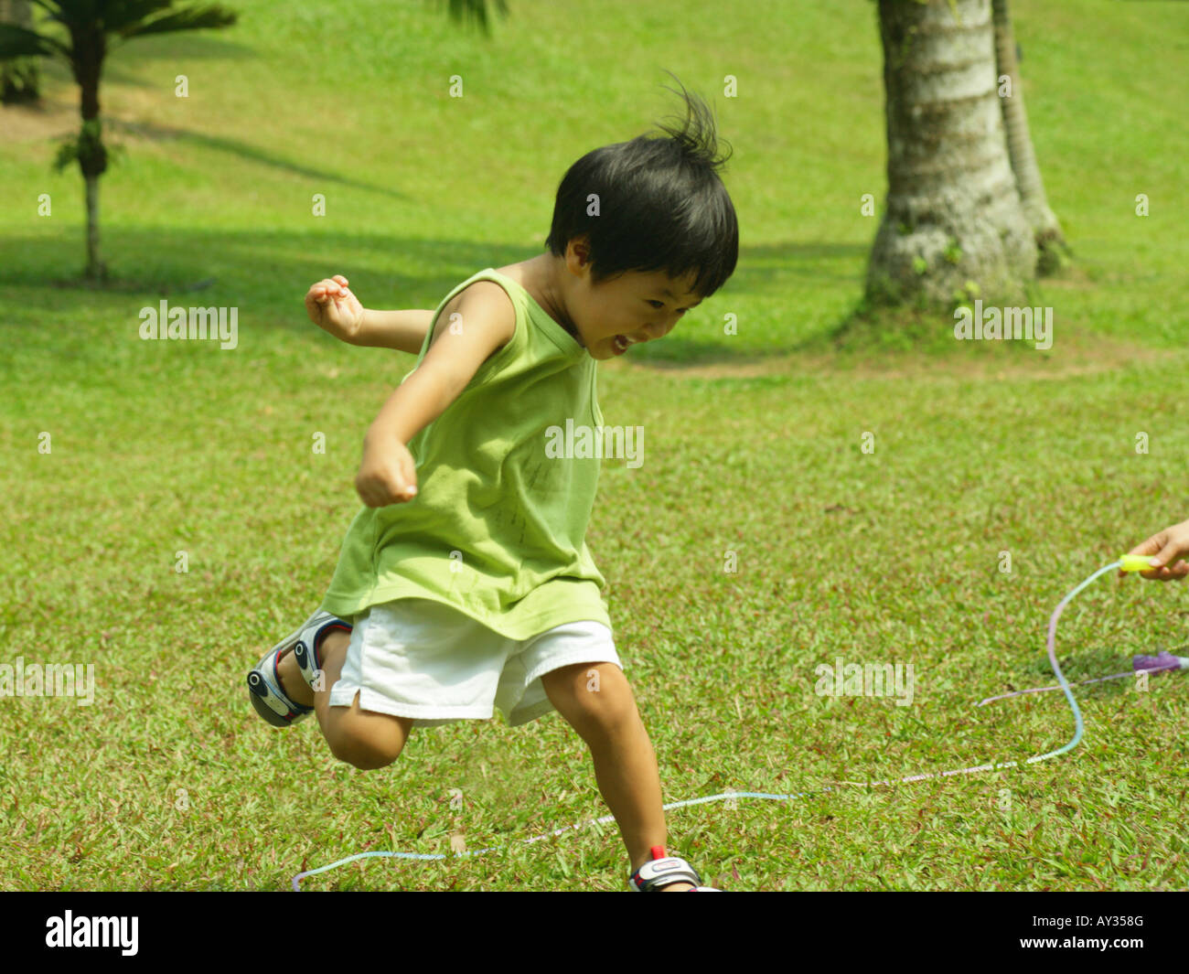 Boy jumping over a jump rope on a lawn Stock Photo Alamy