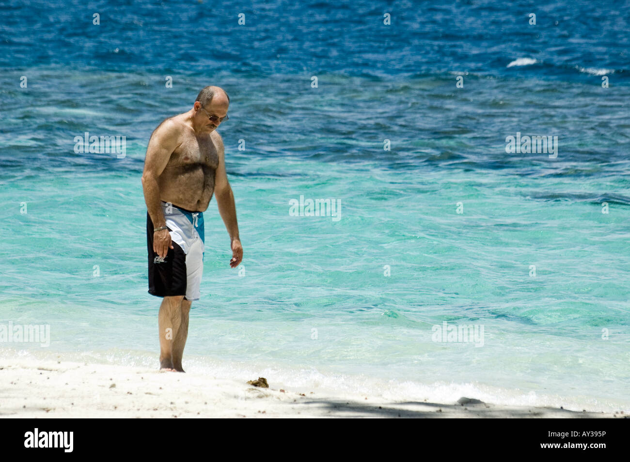 A man is walking along the waterline on the beach of Sepa Island. Stock Photo