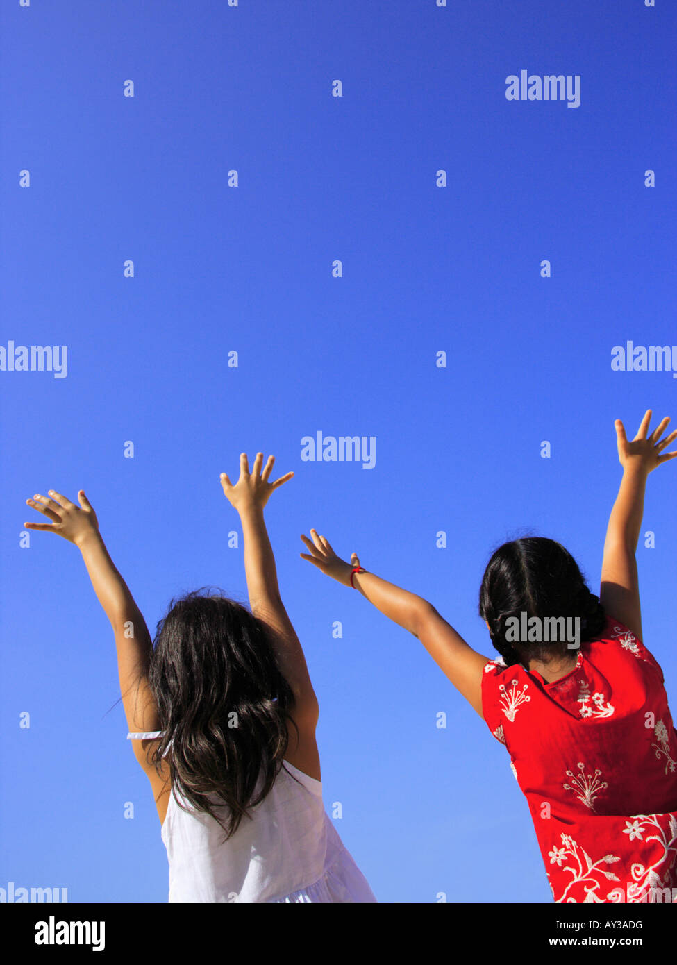 Rear view of two girls standing with their arms raised Stock Photo - Alamy