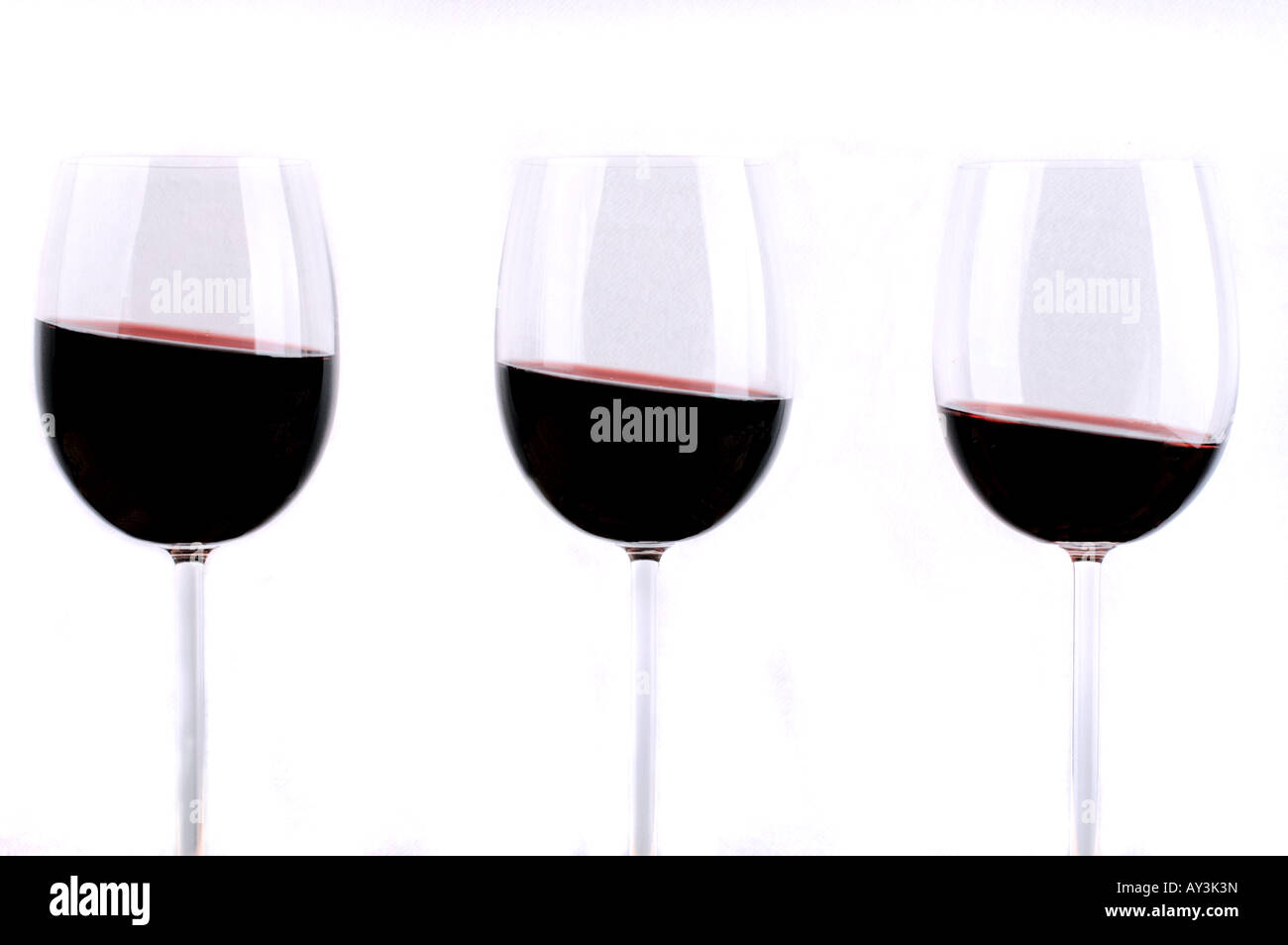 Detail of three glasses of red wine, content slanting / Drei Rotweingläser mit schrägem Inhalt Stock Photo