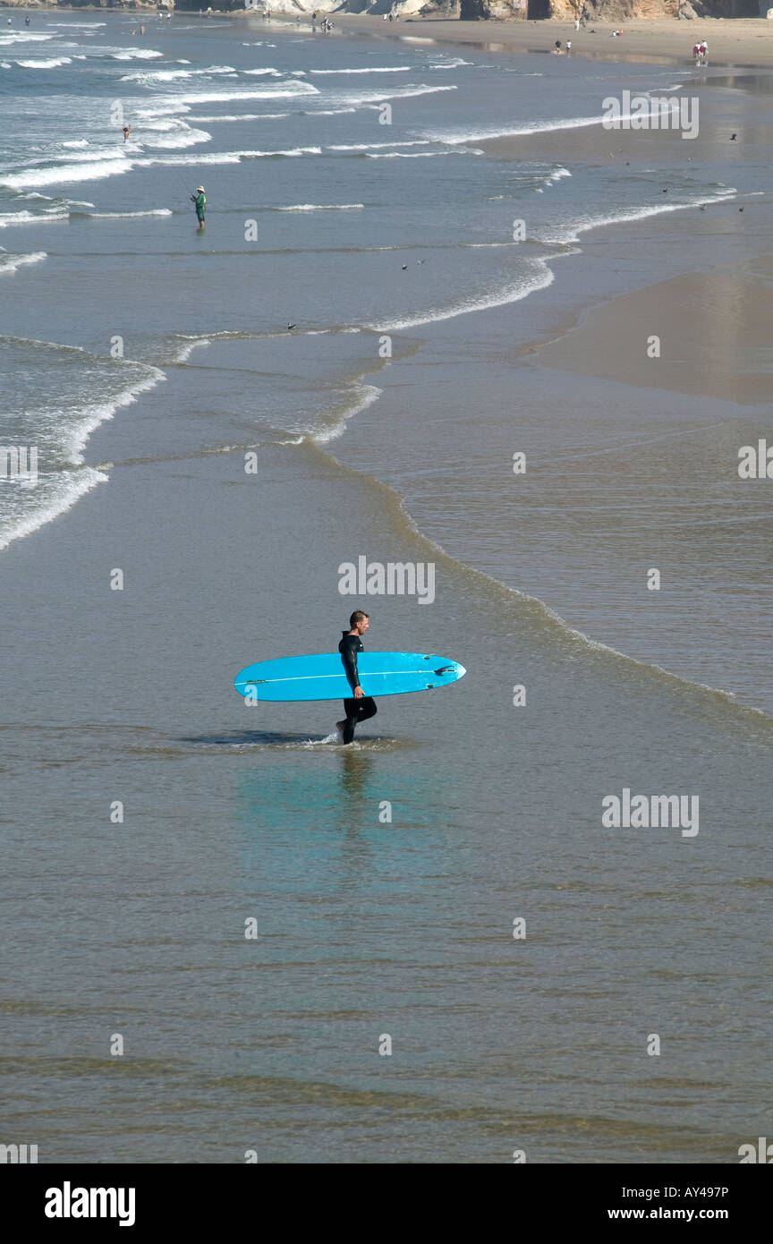 surfer approaches the shore with his blue urfboard Stock Photo
