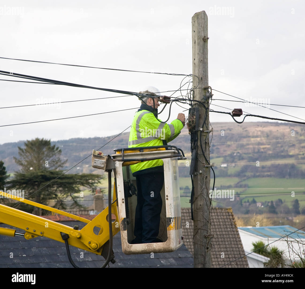 Engineer working at height using mechanical lift repairing telephone junction box Wales UK Stock Photo