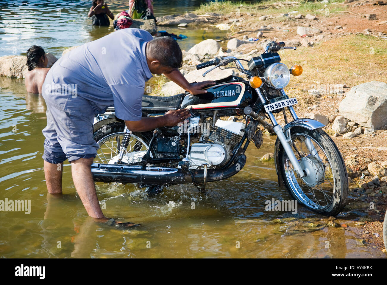 Man washing a motorcycle in a river, Madurai, Tamil Nadu, India Stock Photo