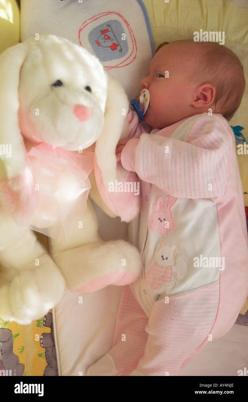 Newborn baby girl with pacifier 0 3 months wearing baby clothing lying in  crib with her favorite stuffed animal Stock Photo - Alamy