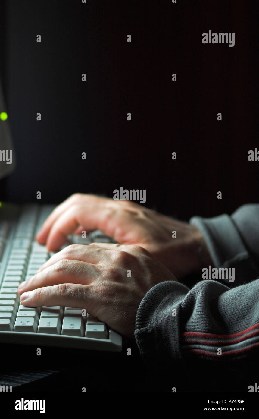 Man using computer hands illuminated by computer monitor Stock Photo