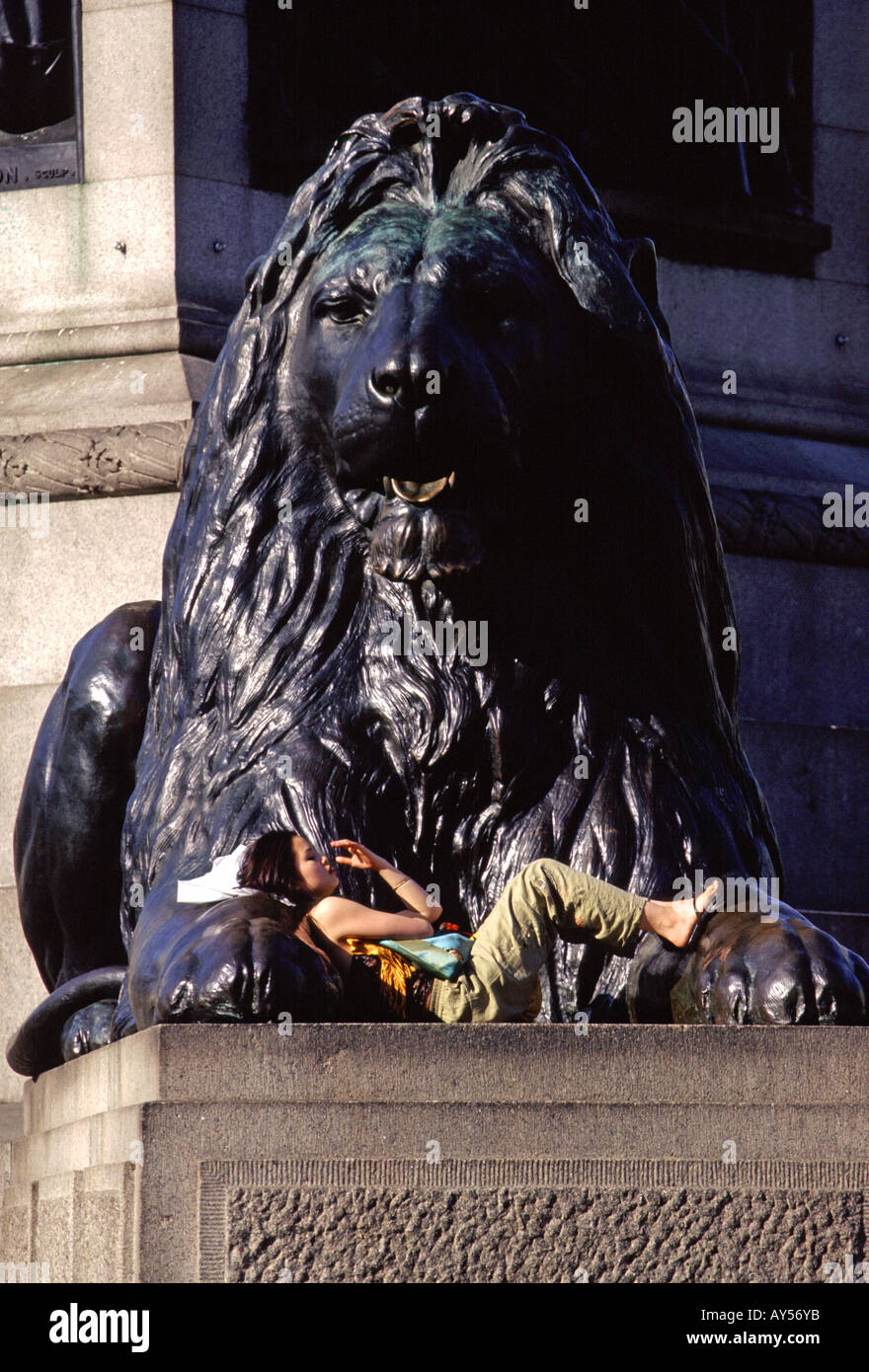 Tourist resting beneath one of the lion statues in Trafalgar Sqaure