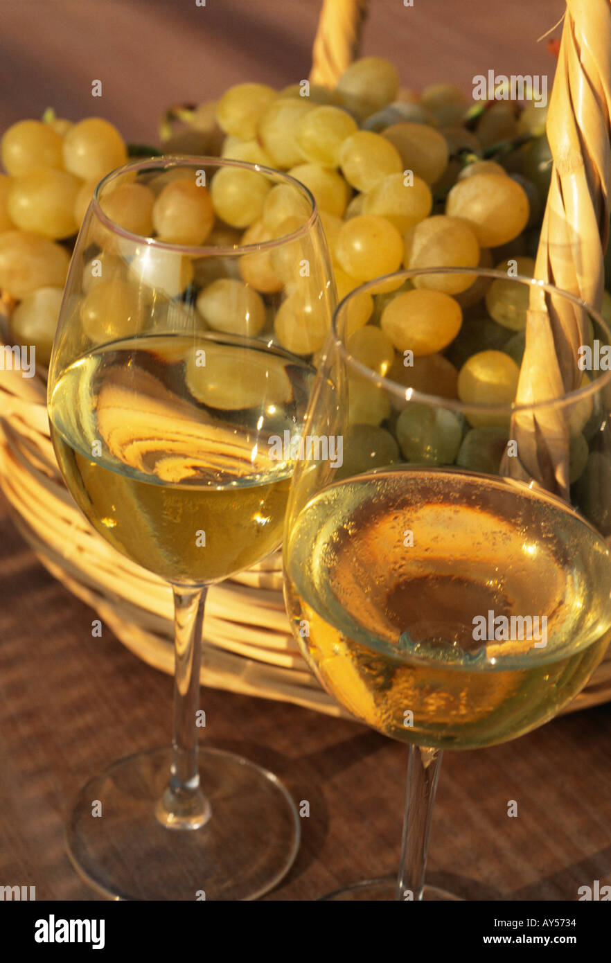 Two glasses of white wine with freshly harvested grapes in a handmade wicker basket Stock Photo