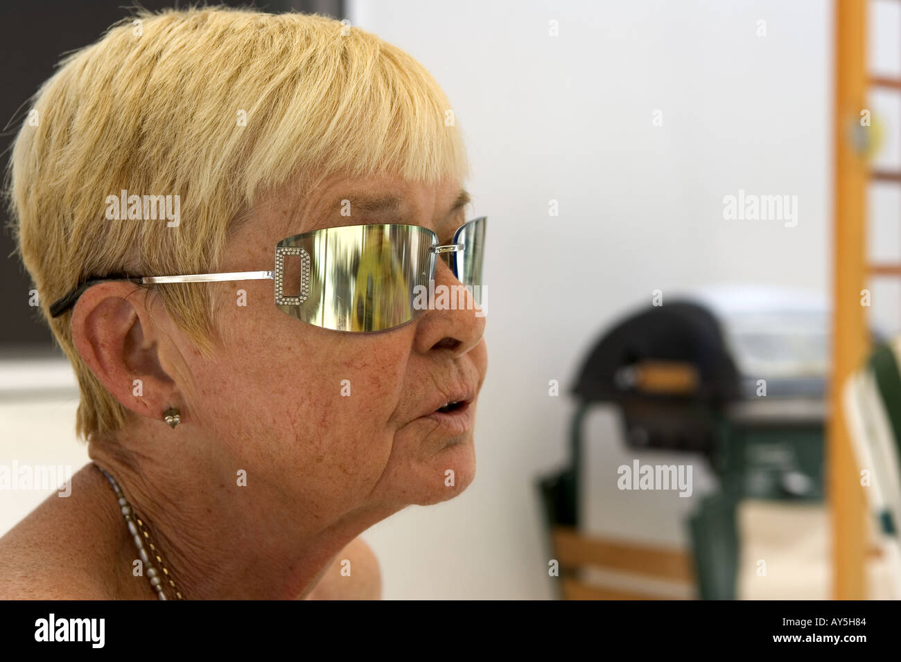 Blonde short haired elderly lady wearing reflective sunglasses Stock Photo