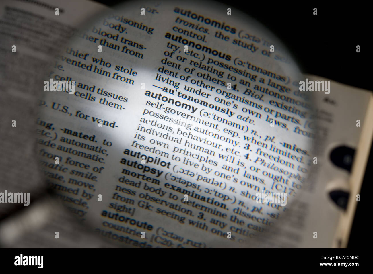 MAGNIFYING GLASS ON DICTIONARY PAGE SHOWING DEFINITION OF THE WORD AUTONOMY Stock Photo