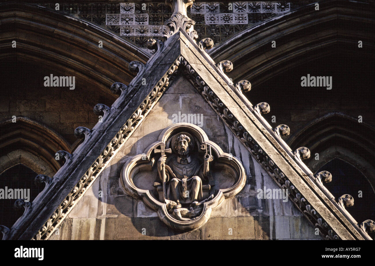 Carved holy figure holding a cross on the exterior of Westminster Abbey London UK Stock Photo