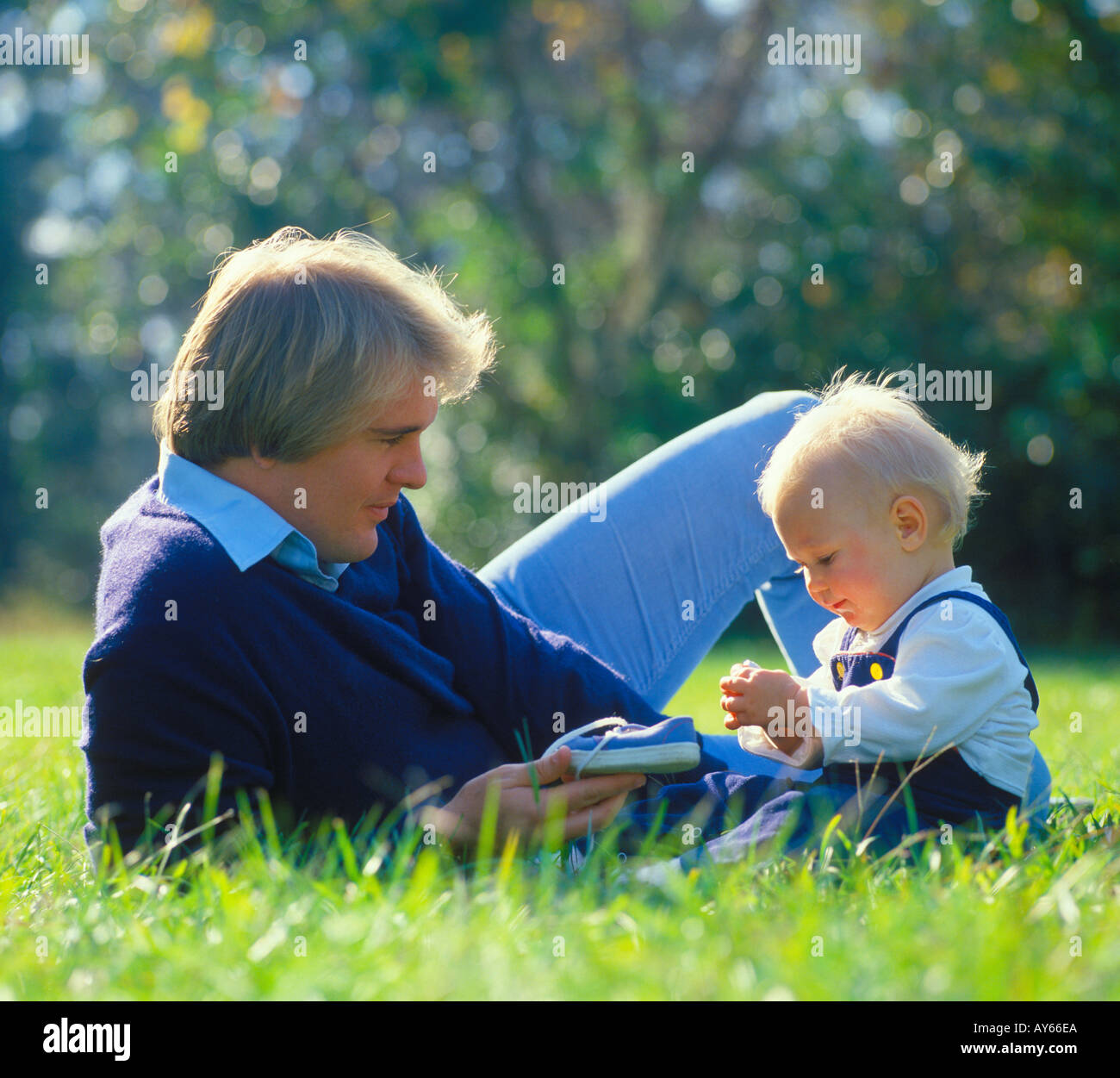 father with baby relaxing on lawn Stock Photo