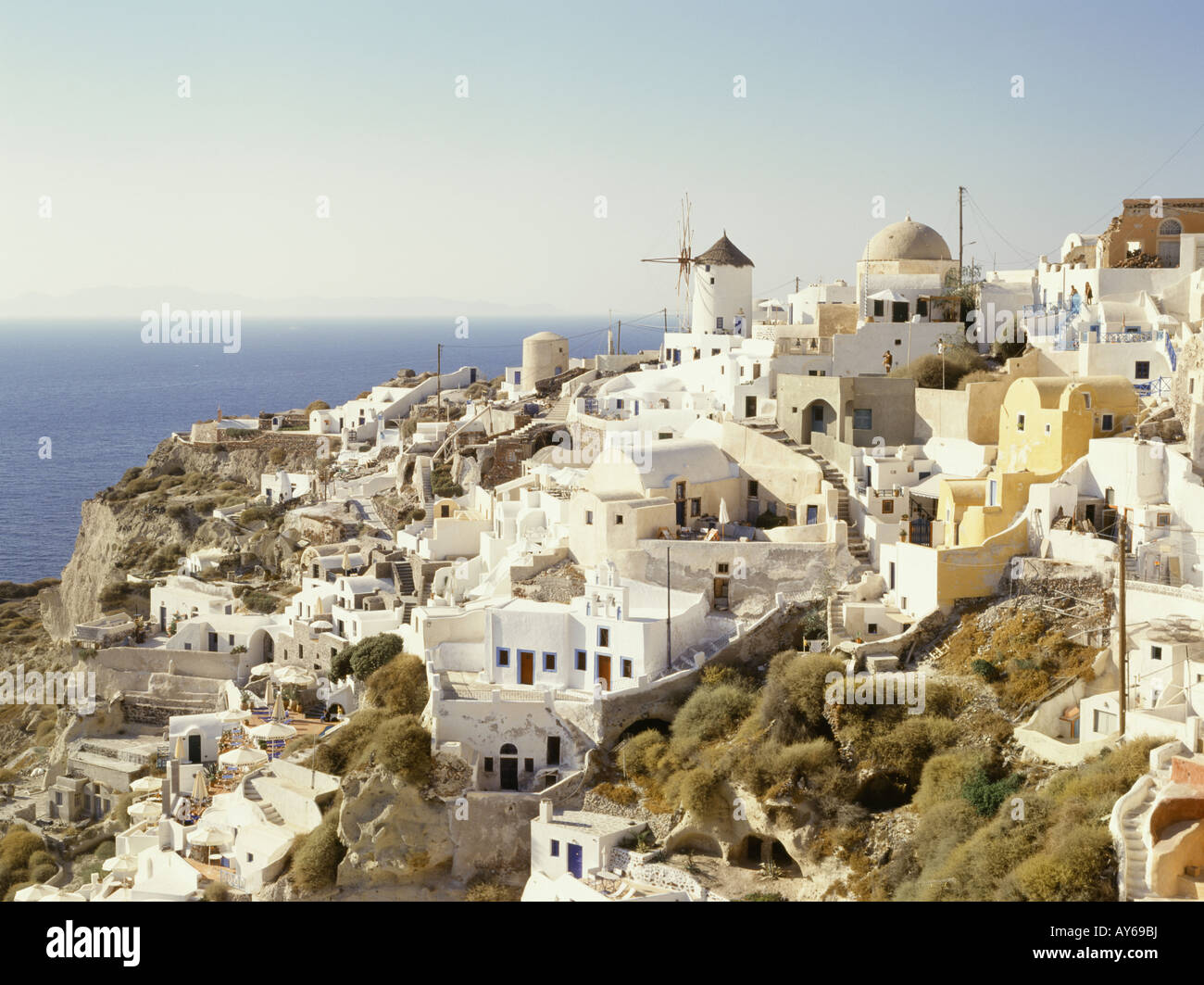 Cyclades Islands. View of white buildings of town perched on hill. Church. Windmill. Distinctive domed roofs. Sea. Stock Photo