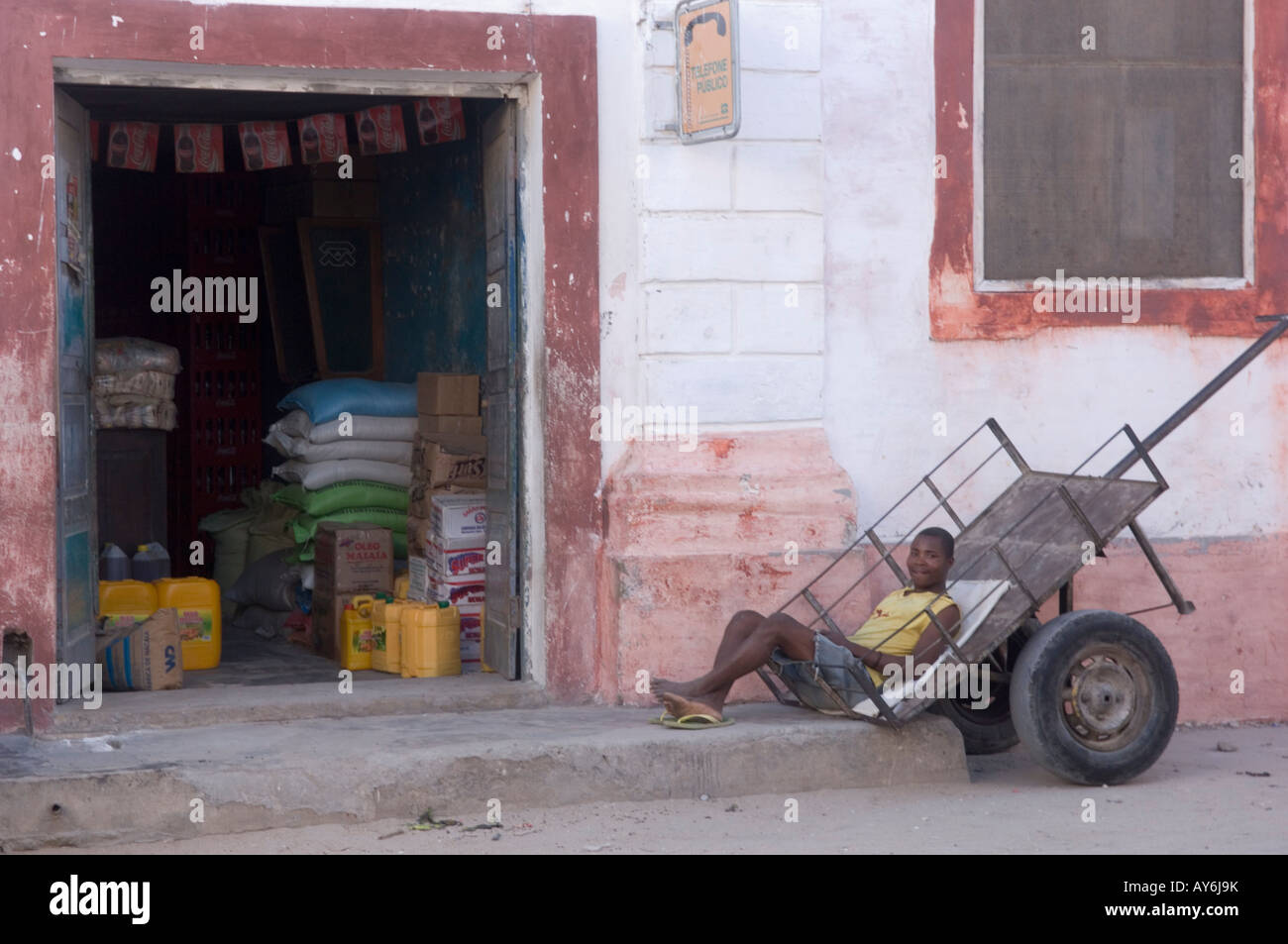 Young man taking a rest in a trailer wagon  in front of his shop. Ilha de Mozambique Stock Photo