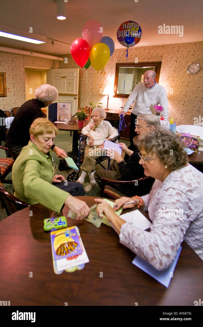 A relative reads birthday cards to centenarian after her 100th birthday party at a nursing home in Stoneham MA with friends Stock Photo