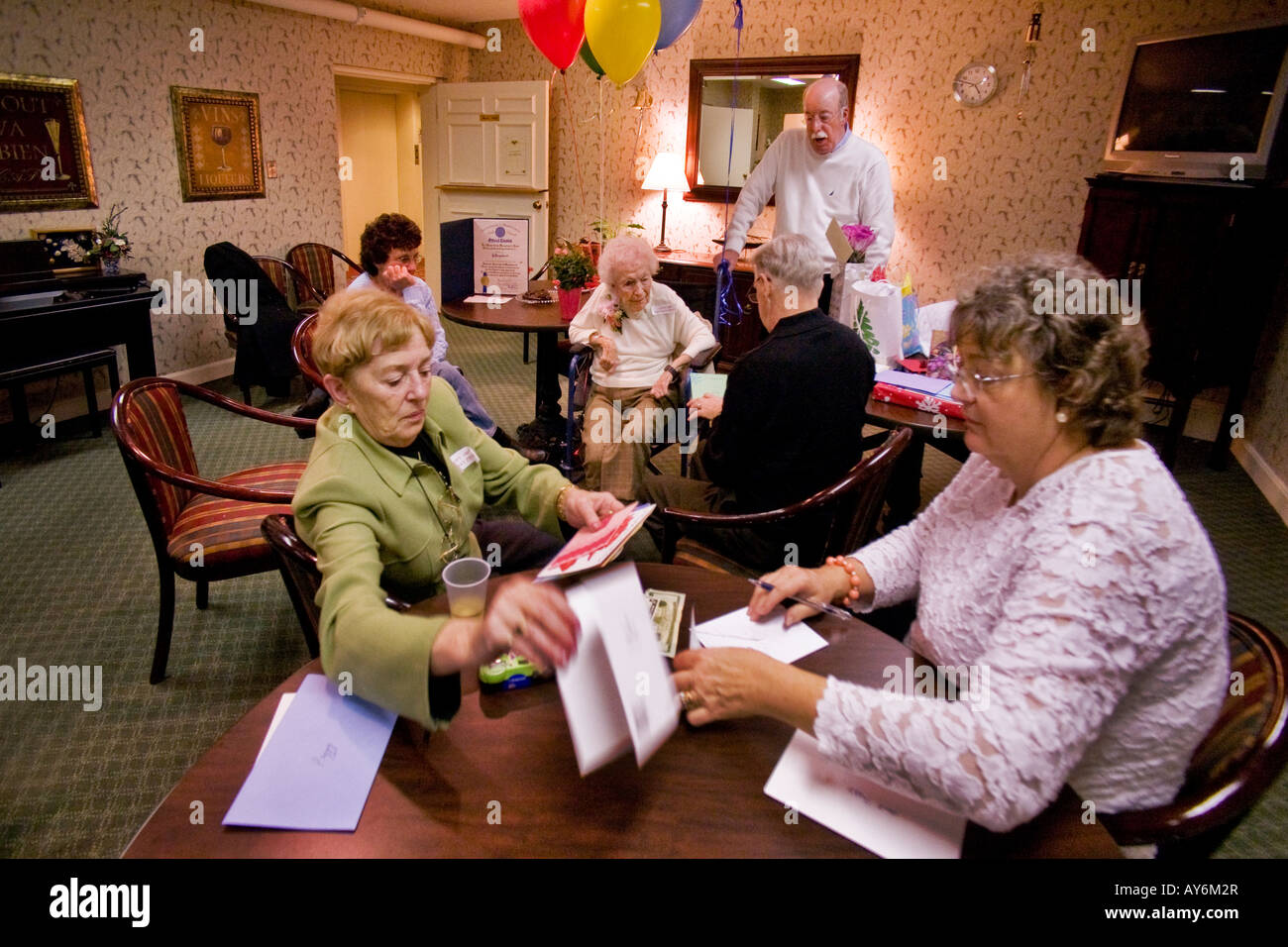 A relative reads birthday cards to centenarian after her 100th birthday party at a nursing home in Stoneham MA with friends Stock Photo