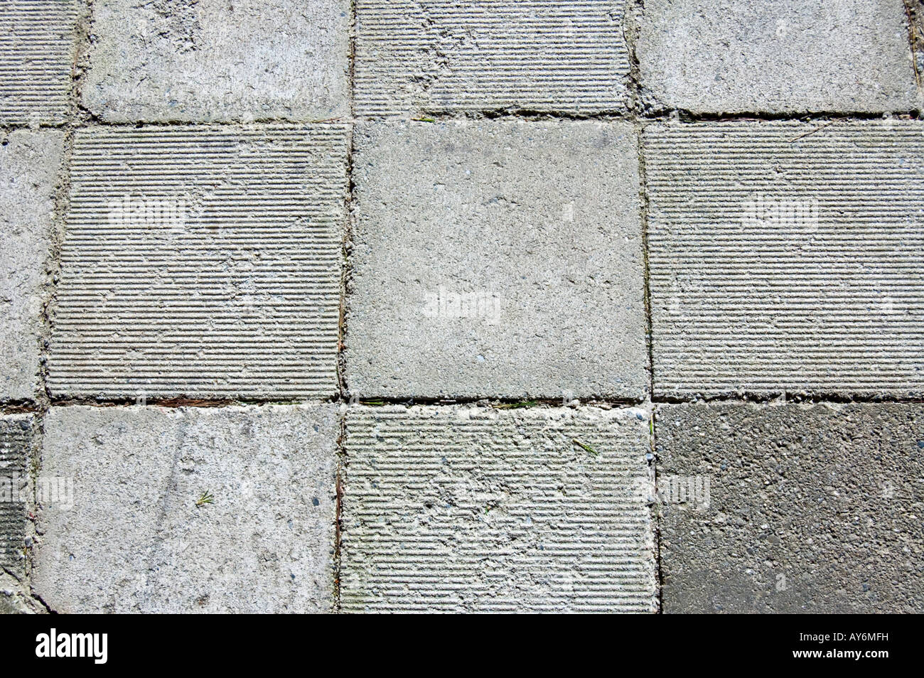 Concrete sidewalk pavers laid out in checkerboard pattern of flat and ribbed textures Stock Photo