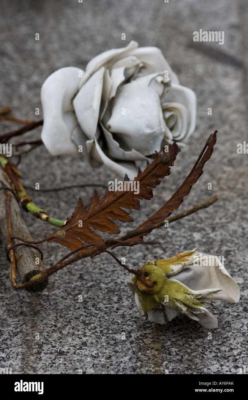 Plastic flowers and metal leaves lie on top of a grave in Montmartre cemetery Stock Photo
