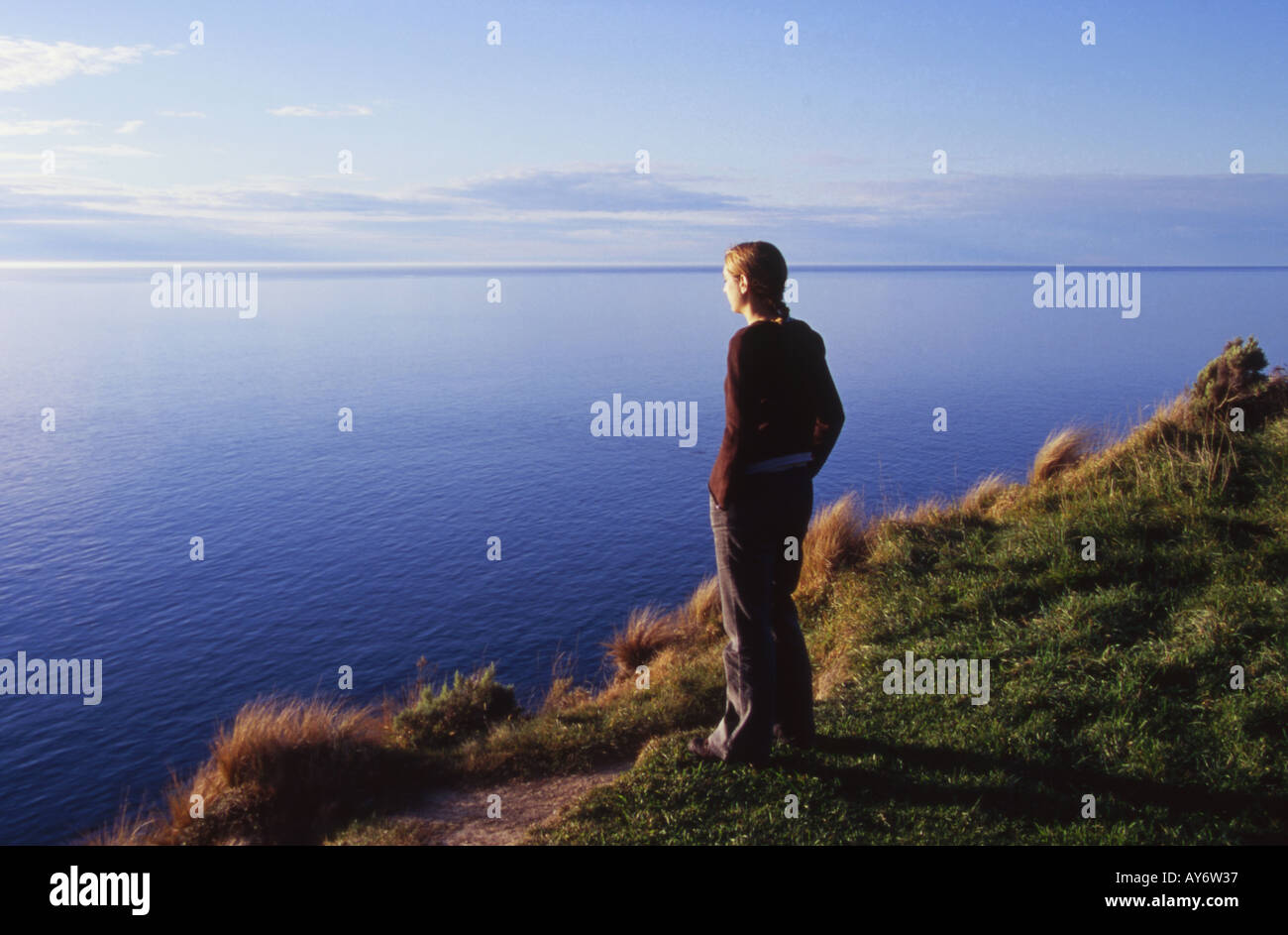 Caucasian Female Standing on Headland looking out to Sea at The Cook Straight New Zealand Stock Photo